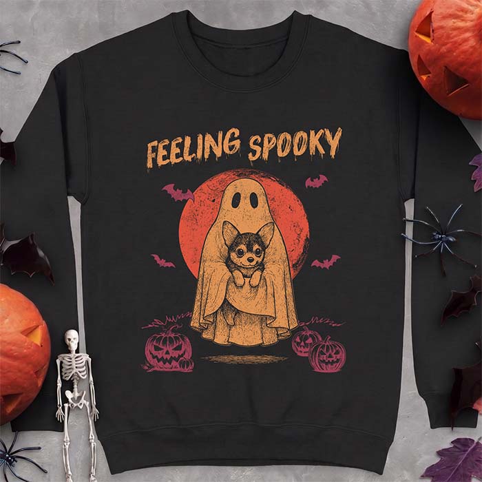 Black sweatshirt with a Halloween graphic of a ghost holding a wide-eyed Corgi puppy in front of a red moon with bats and jack-o-lanterns, with the text Feeling Spooky