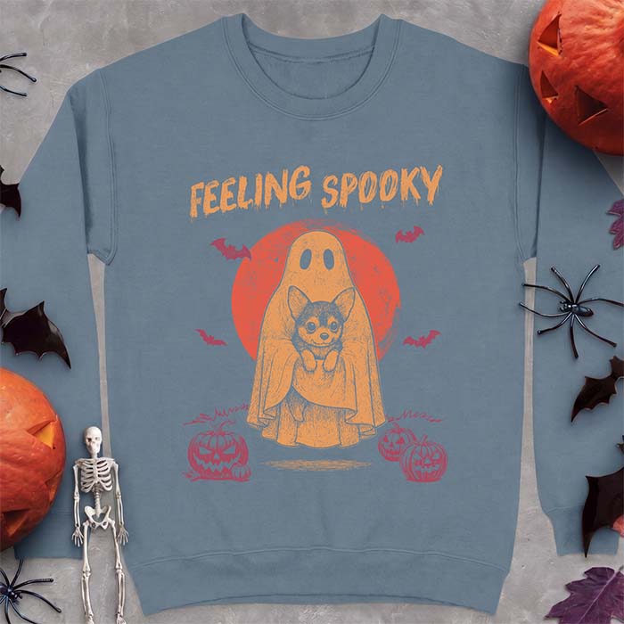Indigo Blue sweatshirt with a Halloween graphic of a ghost holding a wide-eyed Corgi puppy in front of a red moon with bats and jack-o-lanterns, with the text Feeling Spooky
