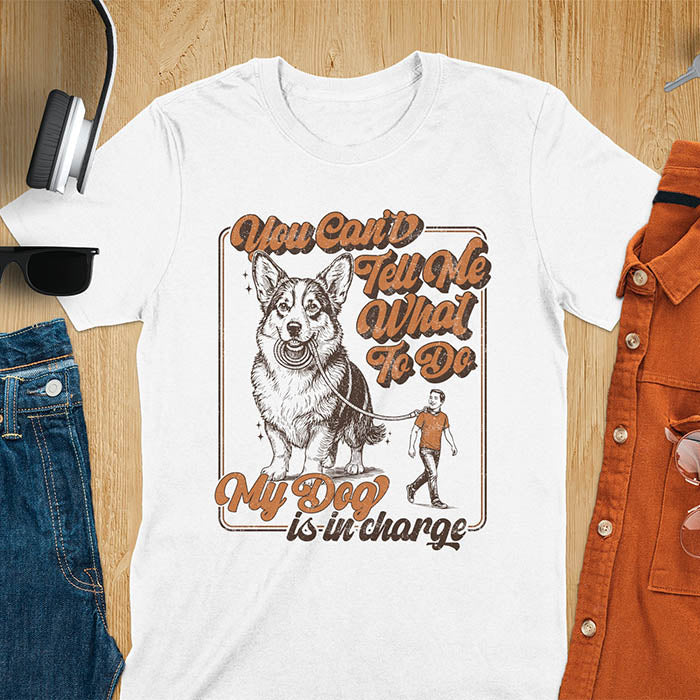 You Can't Tell Me What To Do My Dog Is In Charge text with man being walked on leash by corgi in vintage retro frame graphic on white t-shirt