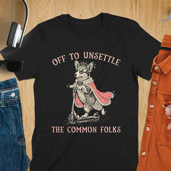 Off To Unsettle The Common Folks text with king corgi wearing crown and red cape on skateboard scooter vintage meme graphic on black t-shirt