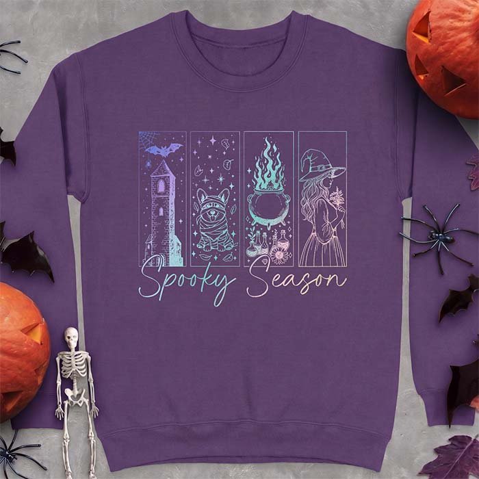 Purple sweatshirt with a four-panel Halloween graphic of a haunted tower, a bandage-wrapped Corgi mummy, a bubbling cauldron with potion bottles and a witch holding flowers, with the text Spooky Season