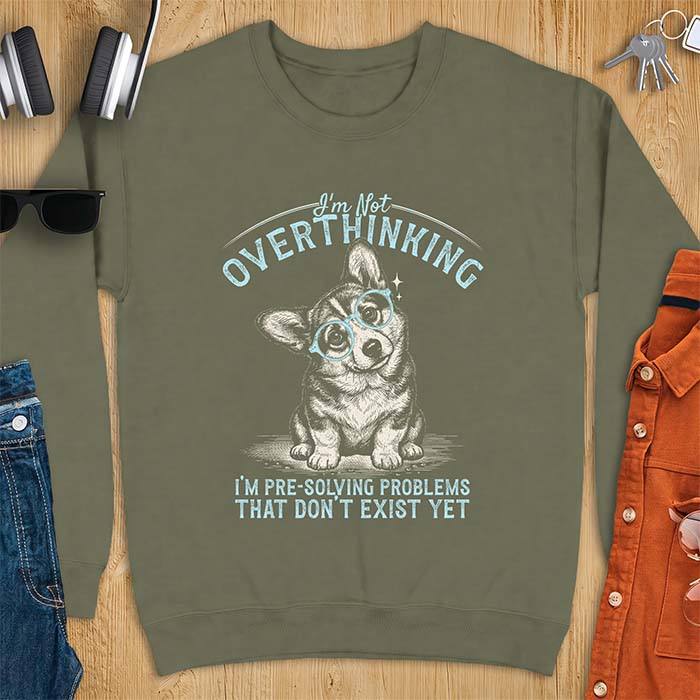 Military Green sweatshirt with a vintage-style illustration of a corgi wearing round glasses, and the text I'm Not Overthinking, I'm Pre-Solving Problems That Do Not Exist Yet.