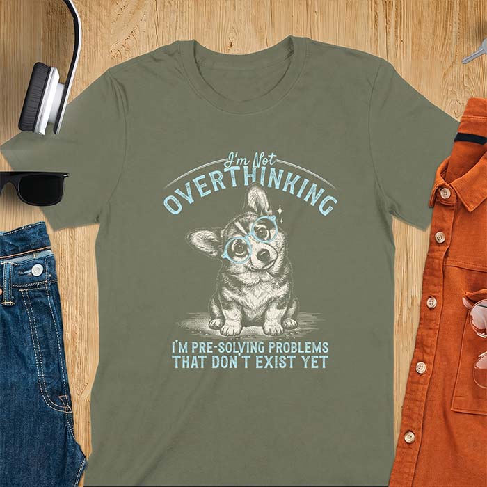 Military Green t-shirt with a vintage-style illustration of a corgi wearing round glasses, and the text I'm Not Overthinking, I'm Pre-Solving Problems That Do Not Exist Yet.