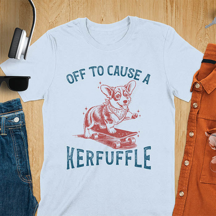 Light blue t-shirt with Off To Cause A Kerfuffle text and cute corgi puppy attempting skateboarding illustration