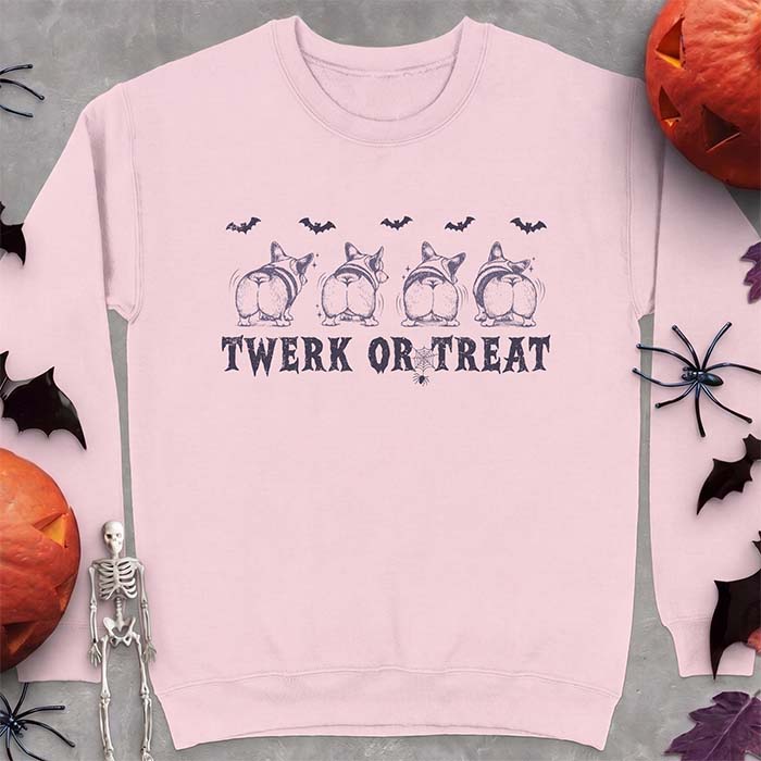 Light Pink sweatshirt with a Halloween graphic of four Corgis viewed from behind shaking their rumps, bats flying above and a spider on a web, with the text Twerk Or Treat