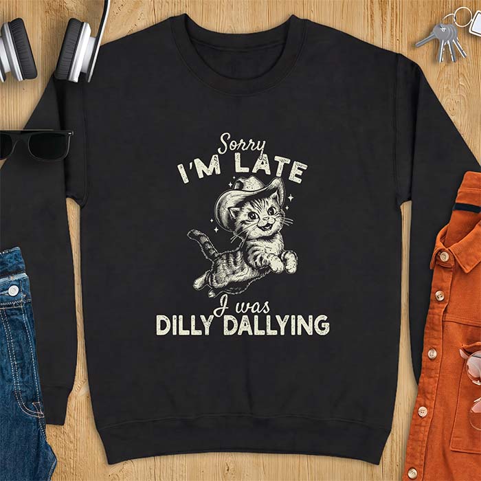 Black sweatshirt with a graphic of a kitten wearing a cowboy hat leaping through the air with sparkle accents and the text Sorry I'm Late I Was Dilly Dallying