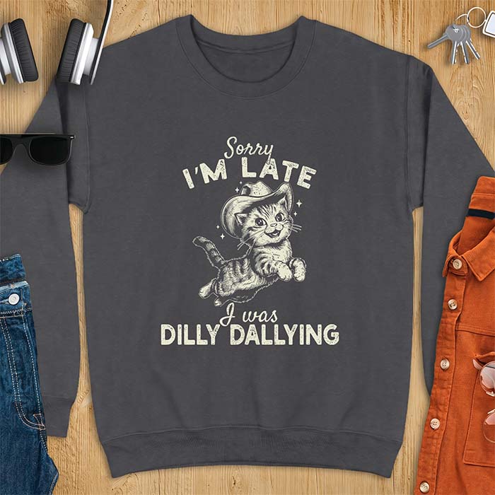 Dark Heather sweatshirt with a graphic of a kitten wearing a cowboy hat leaping through the air with sparkle accents and the text Sorry I'm Late I Was Dilly Dallying