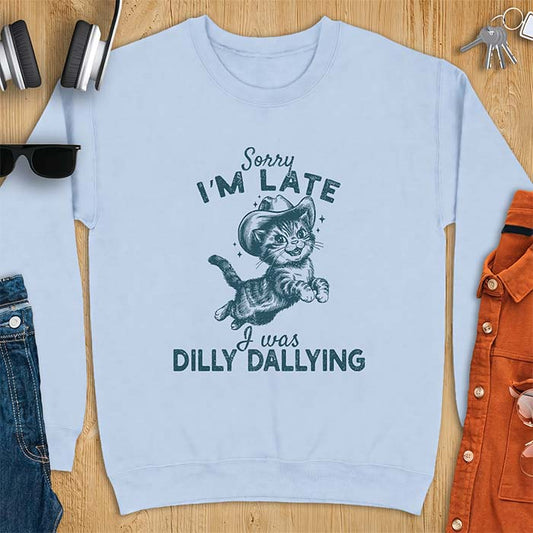 Light Blue sweatshirt with a graphic of a kitten wearing a cowboy hat leaping through the air with sparkle accents and the text Sorry I'm Late I Was Dilly Dallying