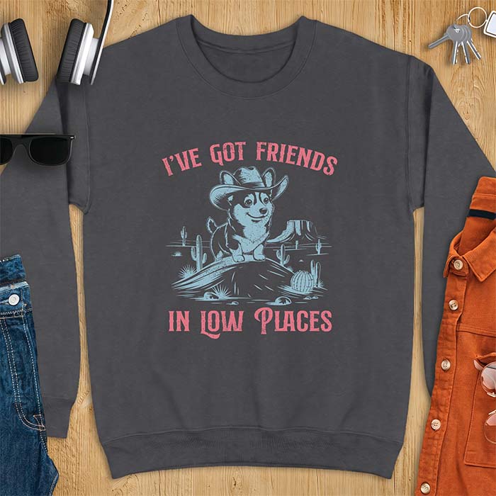 Dark Heather sweatshirt with a western graphic of a corgi puppy in a cowboy hat standing on a desert rock surrounded by cacti and a mesa, with the text I've Got Friends In Low Places printed above and below it.