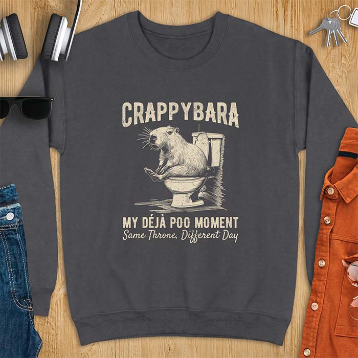 Dark Heather sweatshirt with a toilet humor graphic of a capybara sitting on an old-fashioned toilet, printed with the words Crappybara, My Deja Poo Moment, Same Throne, Different Day.