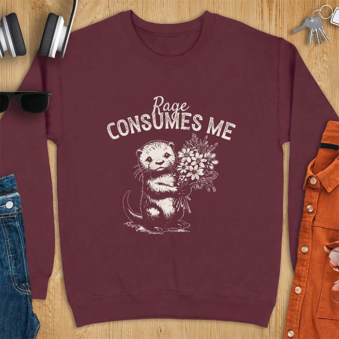 Maroon sweatshirt with a graphic of an otter standing upright holding a bouquet of wildflowers and the text Rage Consumes Me