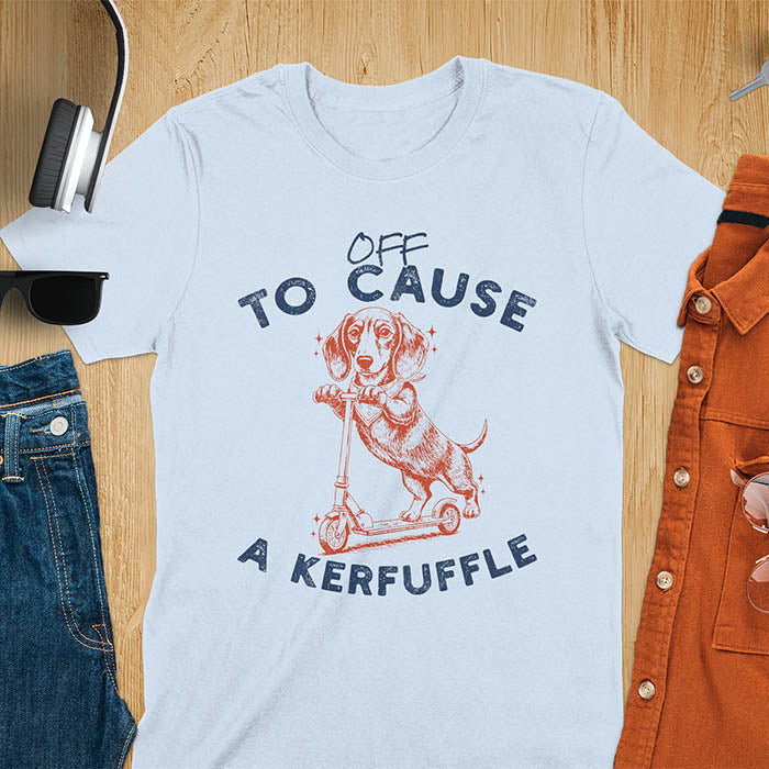 Dachshund on kick scooter illustrated graphic with Off To Cause A Kerfuffle text on light blue t-shirt