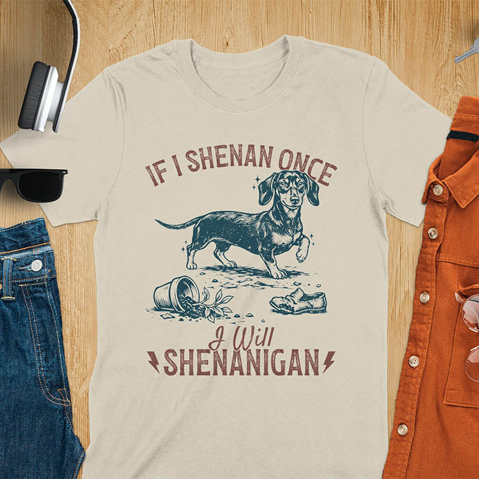 Sand color t-shirt with If I Shenan Once I Will Shenanigan text and Dachshund illustration surrounded by chaos