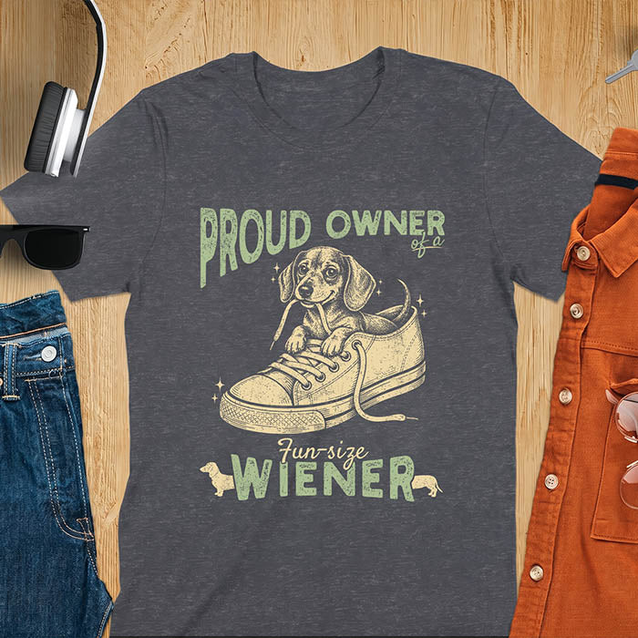 Dark Heather unisex t-shirt with a vintage dachshund graphic of a wiener dog pup sitting inside a classic sneaker, with retro bold lettering reading Proud Owner of a Fun-Size Wiener