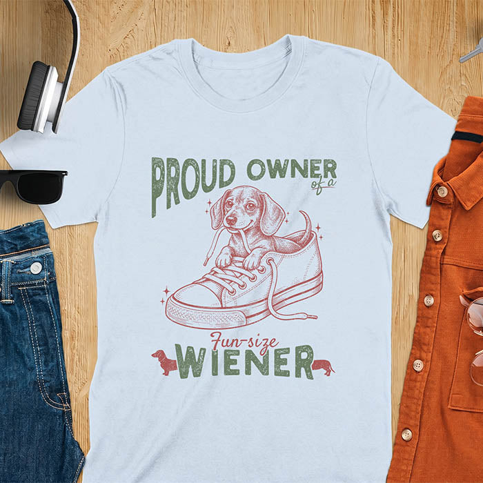 Light Blue unisex t-shirt with a vintage dachshund graphic of a wiener dog pup sitting inside a classic sneaker, with retro bold lettering reading Proud Owner of a Fun-Size Wiener