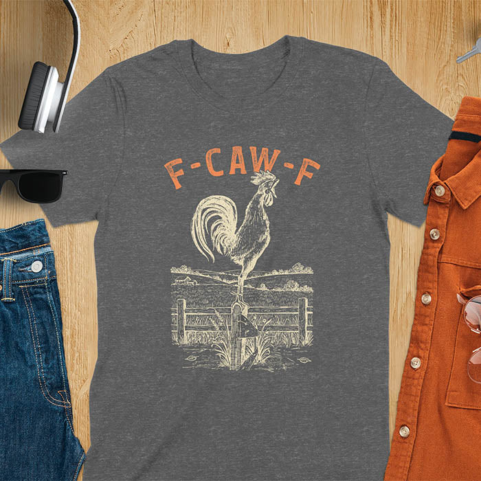 Dark heather t-shirt with F-CAW-F text and detailed rooster illustration standing on wooden fence in vintage farm scene style