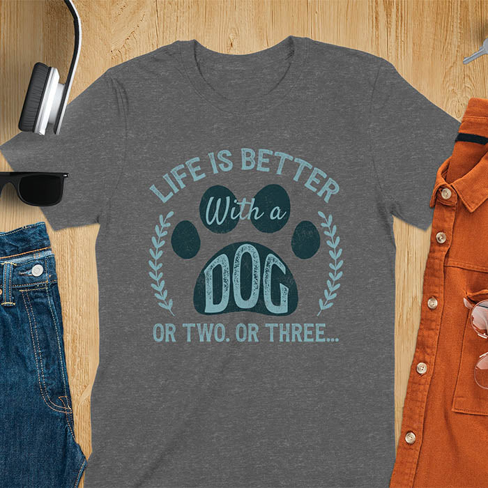 Dark heaher t-shirt featuring large paw print with text inside surrounded by laurel wreath, text reads Life Is Better With A Dog Or Two Or Three