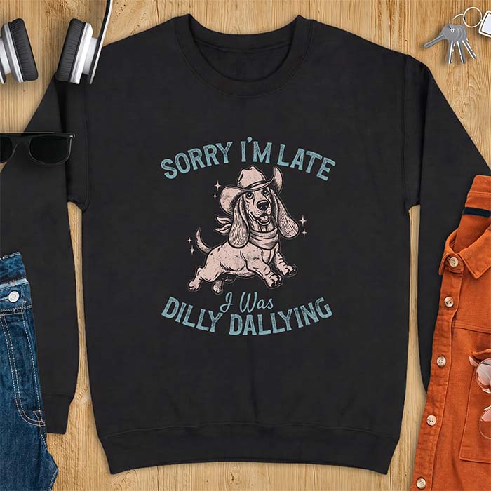 Black sweatshirt with a graphic of a basset hound wearing a cowboy hat and bandana trotting with sparkles around it and the text Sorry I'm Late I Was Dilly Dallying