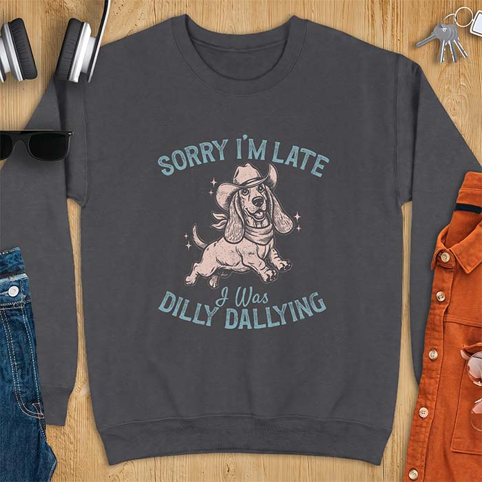 Dark Heather sweatshirt with a graphic of a basset hound wearing a cowboy hat and bandana trotting with sparkles around it and the text Sorry I'm Late I Was Dilly Dallying