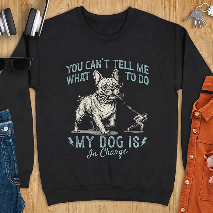 Black sweatshirt with a graphic of a French Bulldog walking a smaller man by the leash and the text “You Can’t Tell Me What To Do. My Dog Is In Charge.”