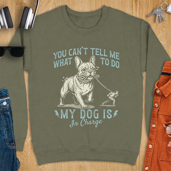 Military Green sweatshirt with a graphic of a French Bulldog walking a smaller man by the leash and the text “You Can’t Tell Me What To Do. My Dog Is In Charge.”