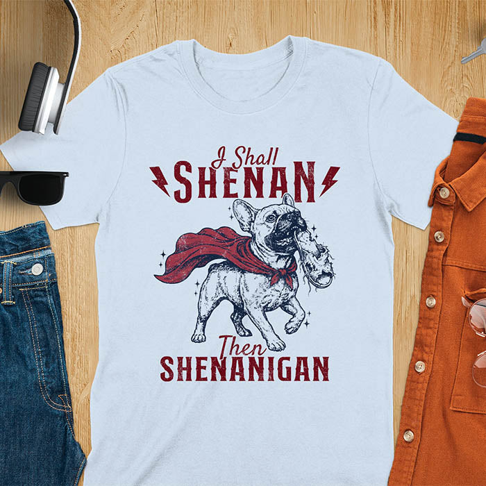 Light Blue tee with vintage Frenchie in red cape biting on a chewed slipper, text reads I Shall Shenan Then Shenanigan
