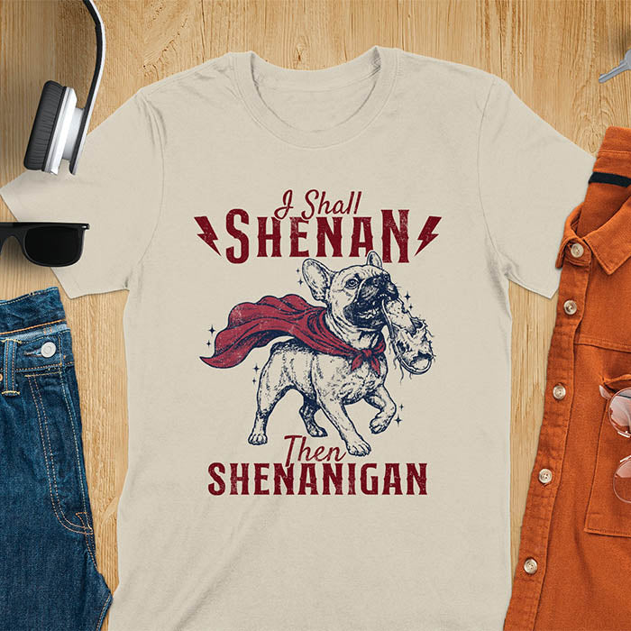Sand color tee with vintage Frenchie in red cape biting on a chewed slipper, text reads I Shall Shenan Then Shenanigan