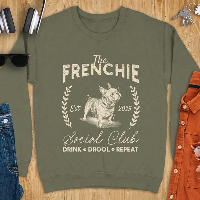 Military Green sweatshirt with a vintage badge graphic of a French Bulldog wearing a collar and tag framed by a laurel wreath, and the text The Frenchie, Est 2025, Social Club, Drink Drool Repeat