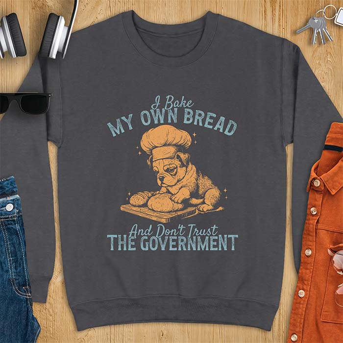 Dark Heather sweatshirt with a graphic of a bulldog wearing a chef hat kneading bread dough on a cutting board and the text I Bake My Own Bread And Don't Trust The Government