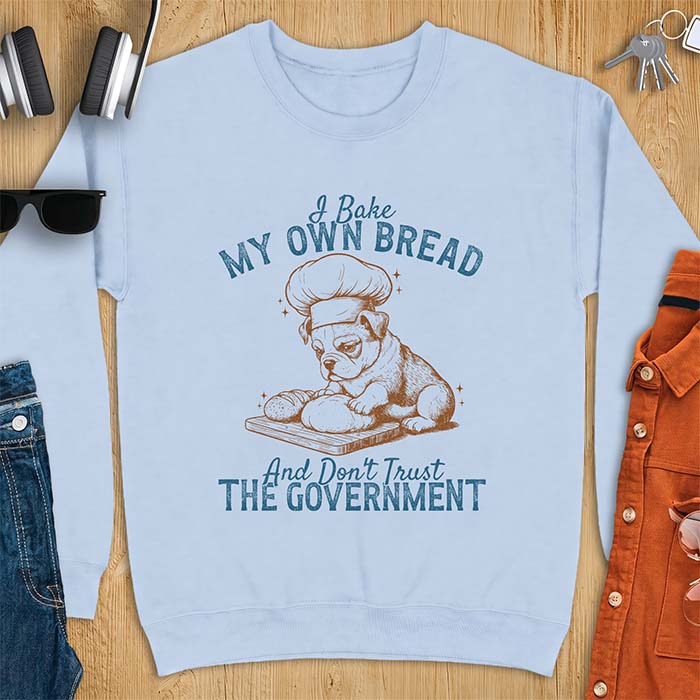 Light Blue sweatshirt with a graphic of a bulldog wearing a chef hat kneading bread dough on a cutting board and the text I Bake My Own Bread And Don't Trust The Government