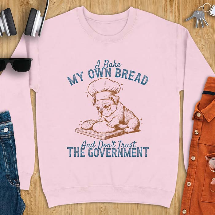 Light Pink sweatshirt with a graphic of a bulldog wearing a chef hat kneading bread dough on a cutting board and the text I Bake My Own Bread And Don't Trust The Government