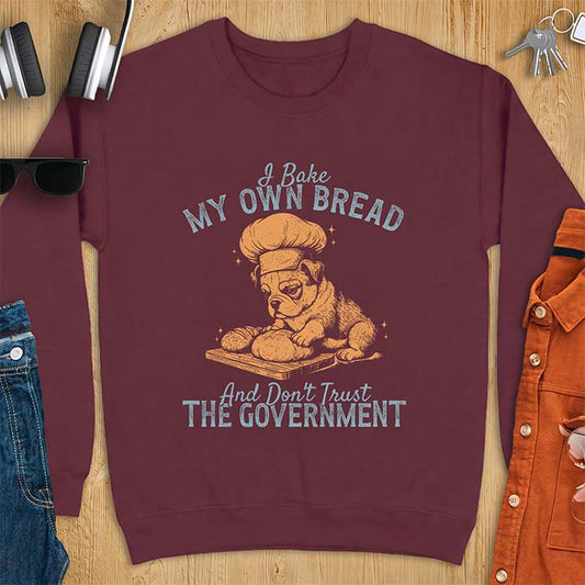 Maroon sweatshirt with a graphic of a bulldog wearing a chef hat kneading bread dough on a cutting board and the text I Bake My Own Bread And Don't Trust The Government