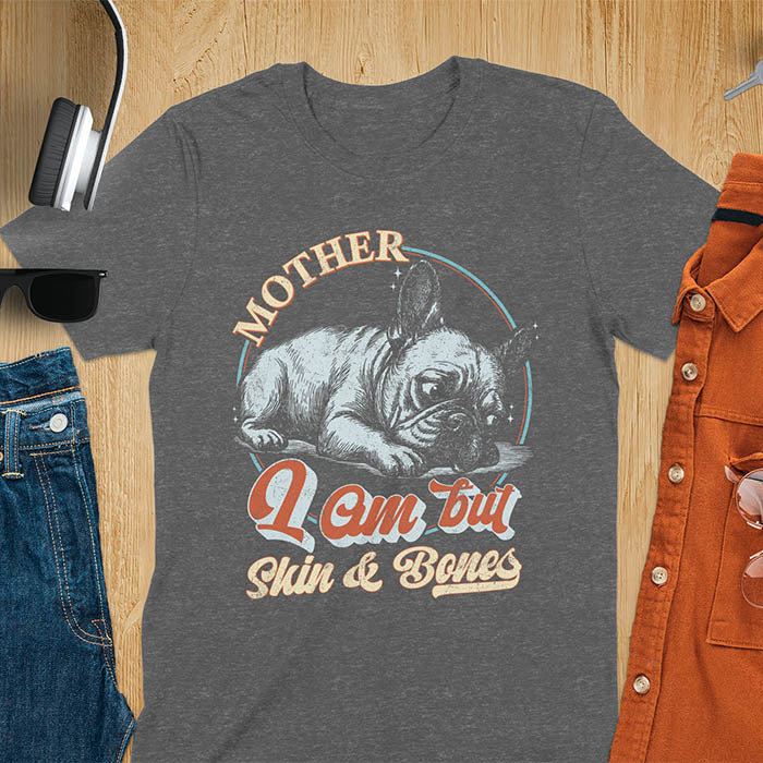 French Bulldog lying down with a sulky expression, with the text Mother I Am But Skin and Bones in retro typography on a dark heather t-shirt