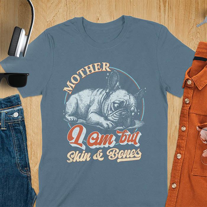 French Bulldog lying down with a sulky expression, with the text Mother I Am But Skin and Bones in retro typography on a indigo blue t-shirt