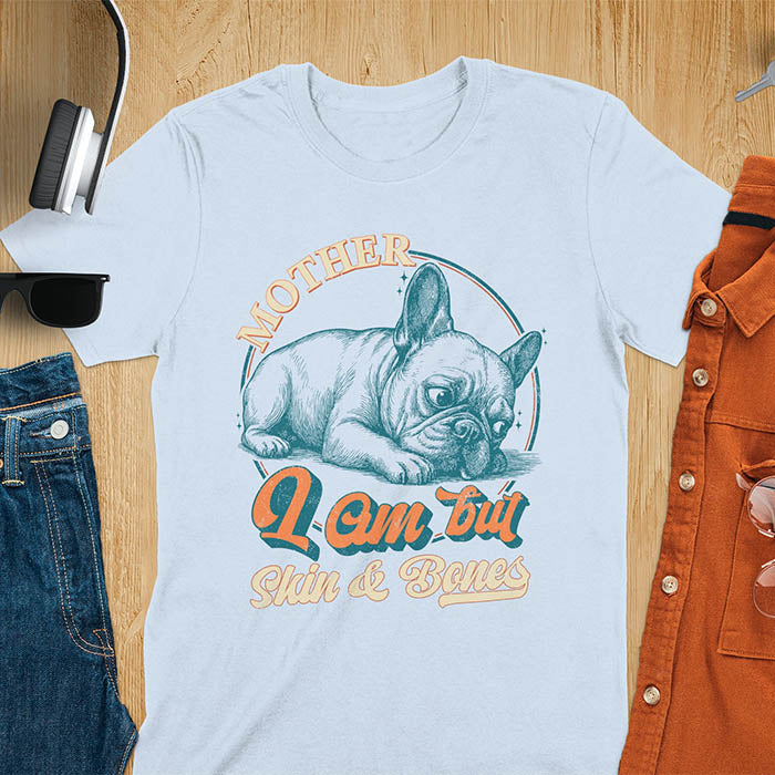 French Bulldog lying down with a sulky expression, with the text Mother I Am But Skin and Bones in retro typography on a light blue t-shirt