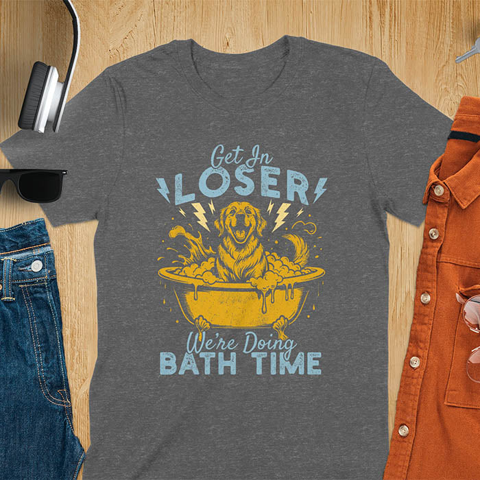 Golden Retriever sitting in a bathtub with soap bubbles and lightning bolts, with the text Get In Loser We're Doing Bath Time on a dark heather t-shirt