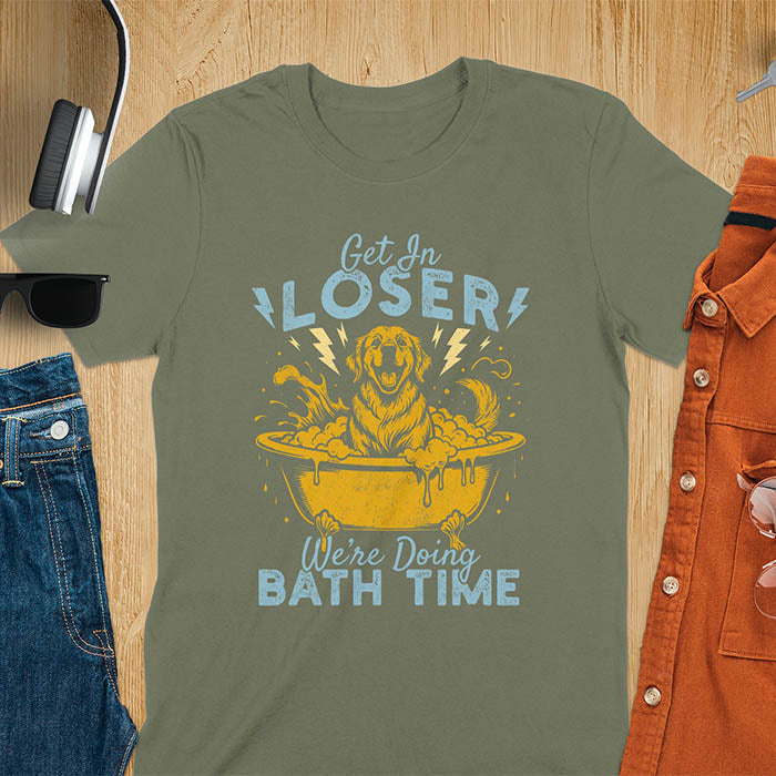 Golden Retriever sitting in a bathtub with soap bubbles and lightning bolts, with the text Get In Loser We're Doing Bath Time on a military green t-shirt