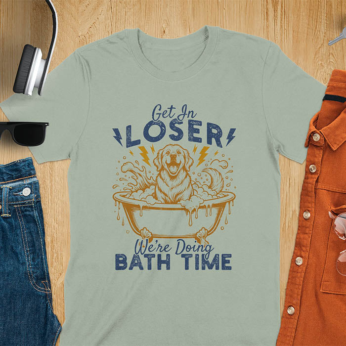 Golden Retriever sitting in a bathtub with soap bubbles and lightning bolts, with the text Get In Loser We're Doing Bath Time on a sage green t-shirt