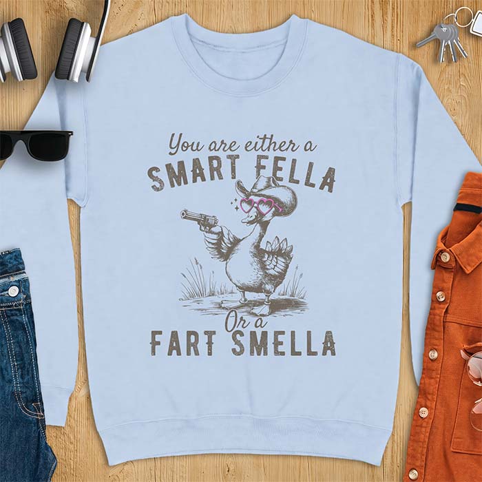 Light Blue sweatshirt with a cowboy goose illustration wearing a hat and pink heart shaped sunglasses, holding a revolver, and the text You Are Either A Smart Fella Or A Fart Smella