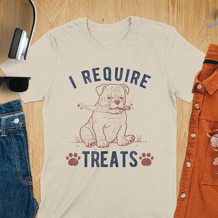 Sand color tee with "I Require Treats" text and grumpy bulldog puppy holding knife in mouth and paw prints vintage graphic