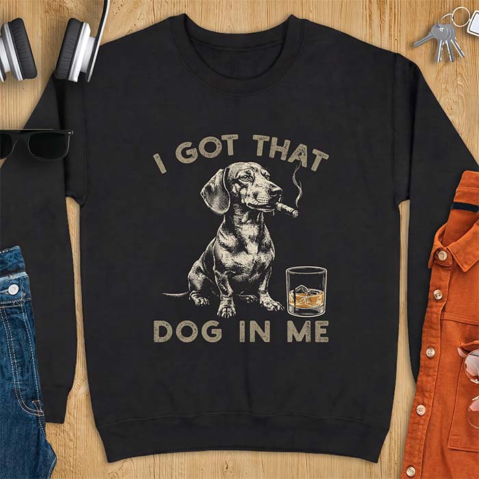 Black sweatshirt with a graphic of a dachshund sitting with a cigar in its mouth and a glass of whiskey beside it and the text I Got That Dog In Me