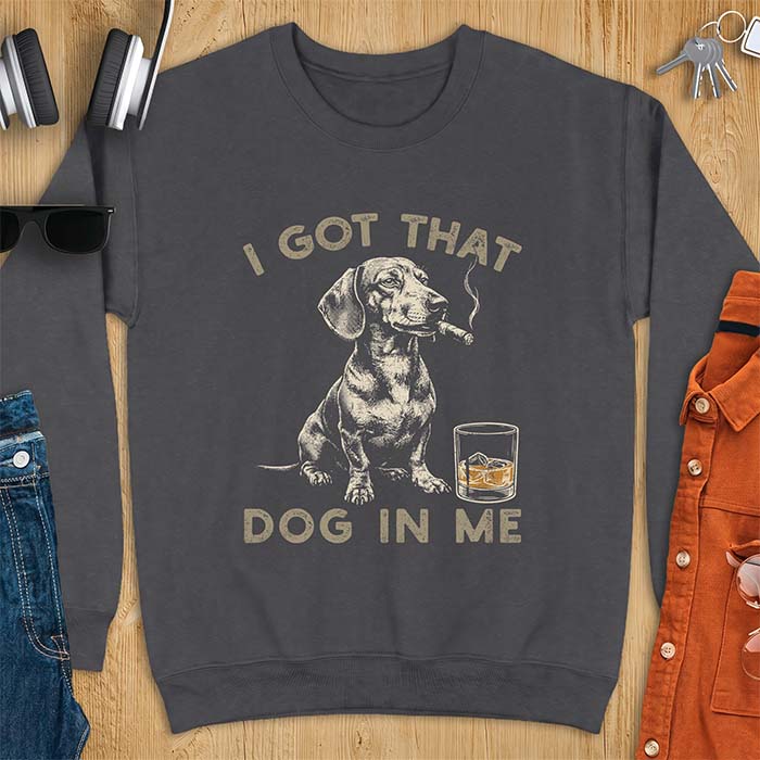 Dark Heather sweatshirt with a graphic of a dachshund sitting with a cigar in its mouth and a glass of whiskey beside it and the text I Got That Dog In Me