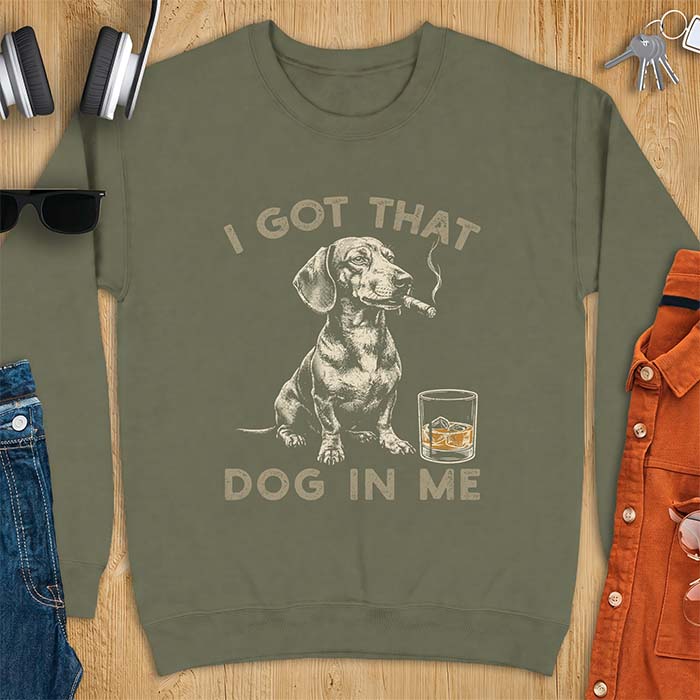 Military Green sweatshirt with a graphic of a dachshund sitting with a cigar in its mouth and a glass of whiskey beside it and the text I Got That Dog In Me