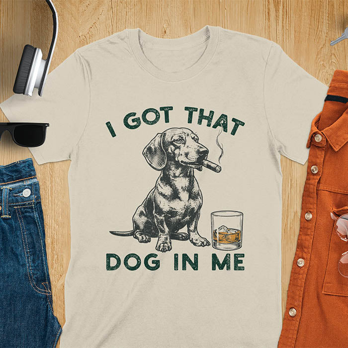 Sand t-shirt with a vintage graphic of a dachshund smoking a cigar next to a whisky glass, with the text I Got That Dog In Me