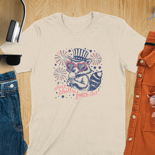 A sand color t-shirt with a raccoon in a patriotic top hat & heart sunglasses, holding an ice cream cone. Fireworks burst around it. Text: "JUST CHILL THE FOURTH OUT". This raccoon cuteness tee is a funny 4th of July fourth of july shirt for chill the 4th out. A fireworks shirt, patriotic merica tee & freedom t shirt for independence day. Has vintage aesthetics, a funny patriot animal person gift or mom gift among 4th of july shirts.
