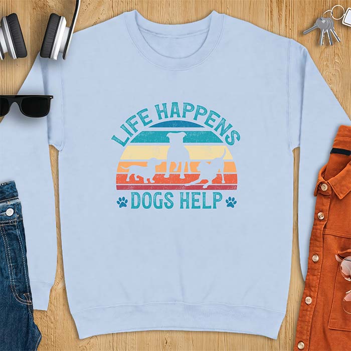 Light Blue sweatshirt with a retro striped sunset graphic of three dog silhouettes trotting together and paw prints on either side and the text Life Happens Dogs Help