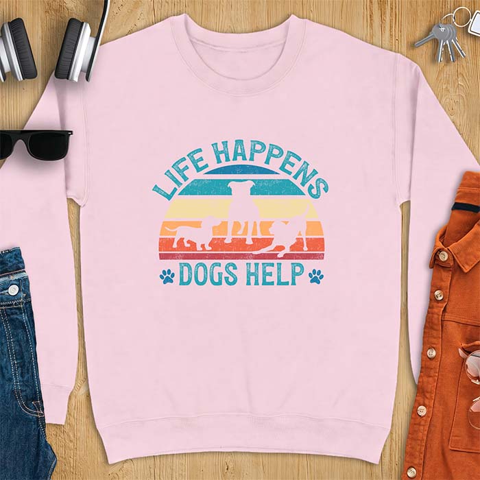 Light Pink sweatshirt with a retro striped sunset graphic of three dog silhouettes trotting together and paw prints on either side and the text Life Happens Dogs Help
