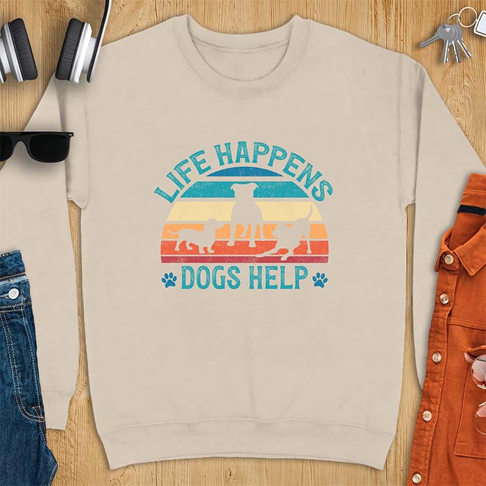 Sand sweatshirt with a retro striped sunset graphic of three dog silhouettes trotting together and paw prints on either side and the text Life Happens Dogs Help