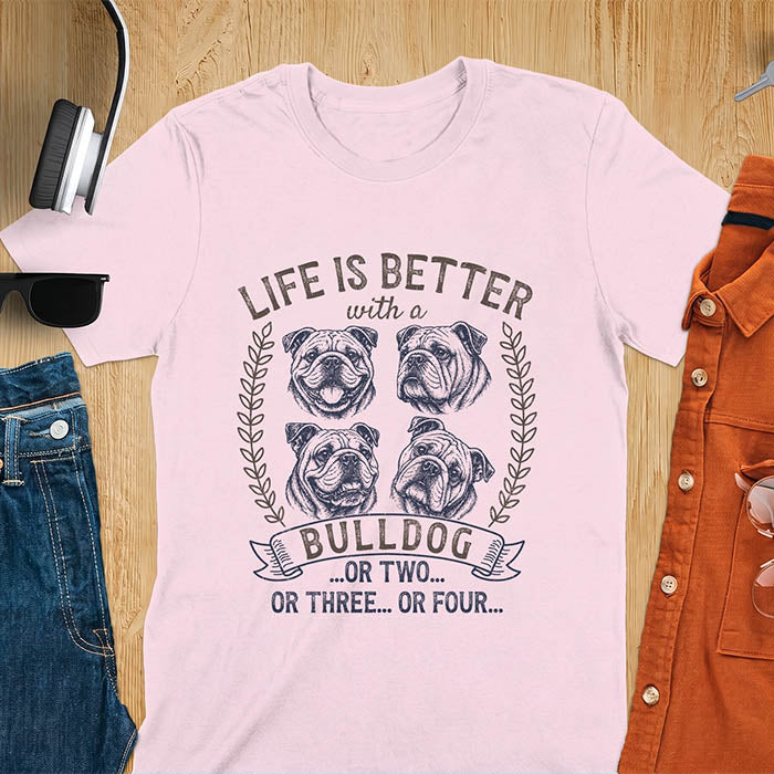 Light Pink unisex t-shirt with distressed vintage graphic featuring four Bulldog portrait illustrations in a two-by-two grid framed by laurel branches, text reads Life Is Better with a Bulldog or two or three or four
