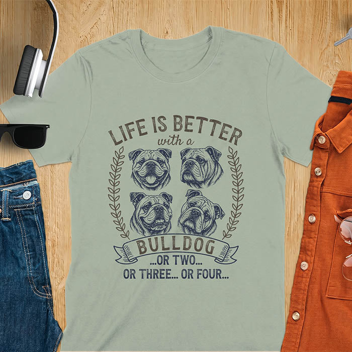 Sage unisex t-shirt with distressed vintage graphic featuring four Bulldog portrait illustrations in a two-by-two grid framed by laurel branches, text reads Life Is Better with a Bulldog or two or three or four